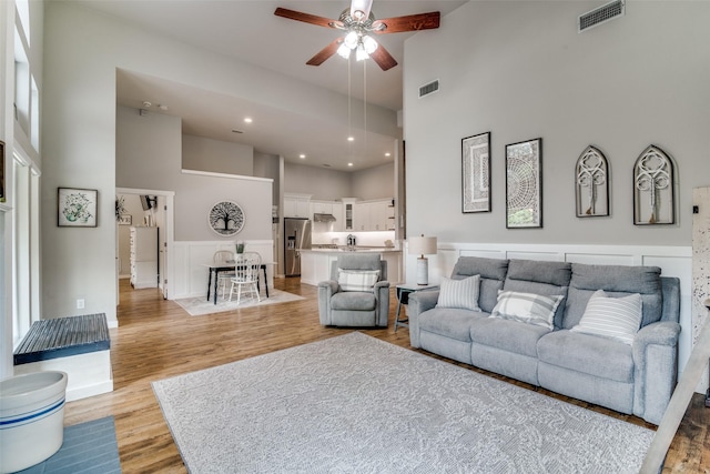 living area featuring visible vents, a high ceiling, recessed lighting, light wood-type flooring, and a ceiling fan