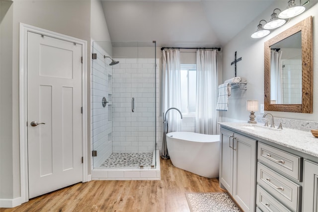 full bathroom featuring a freestanding tub, a shower stall, vaulted ceiling, wood finished floors, and vanity