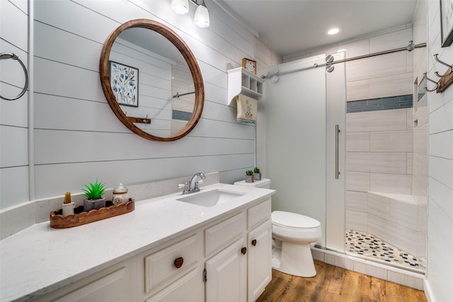 bathroom with vanity, toilet, recessed lighting, a shower stall, and wood finished floors