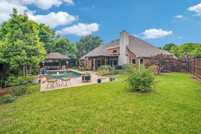 rear view of house with a fenced backyard, a chimney, a patio area, a gazebo, and a yard