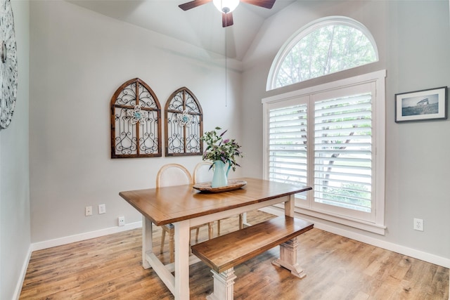 dining room with baseboards, a ceiling fan, light wood finished floors, and high vaulted ceiling