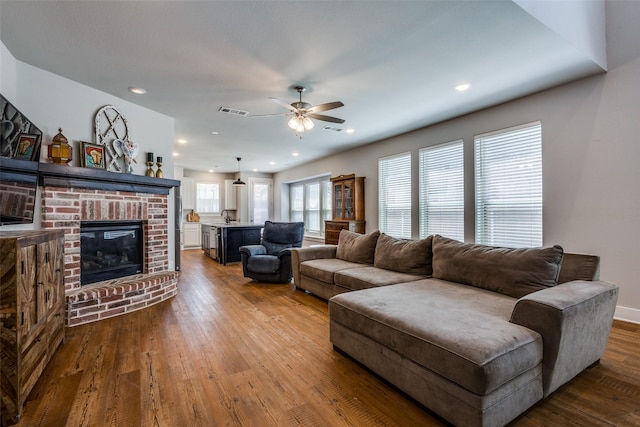 living room featuring ceiling fan, a fireplace, dark wood-style floors, and visible vents