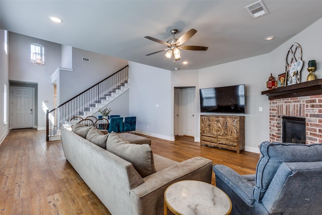 living room with visible vents, baseboards, ceiling fan, stairway, and hardwood / wood-style flooring