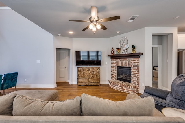 living area featuring visible vents, wood finished floors, a fireplace, baseboards, and ceiling fan