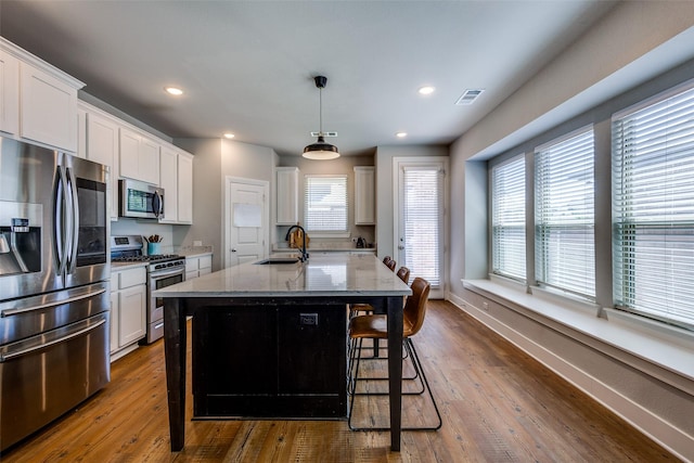 kitchen with visible vents, appliances with stainless steel finishes, light stone countertops, a sink, and white cabinets