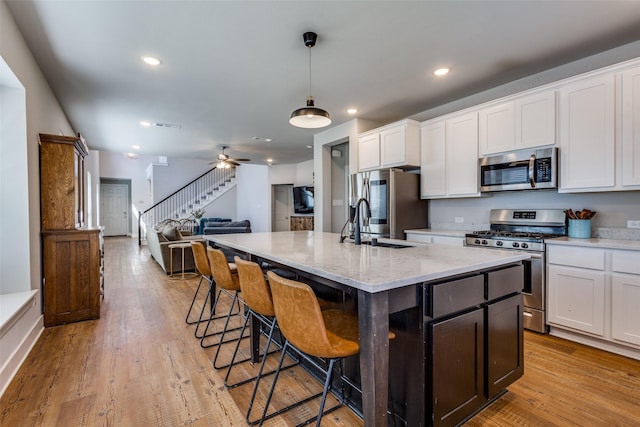 kitchen featuring white cabinets, open floor plan, appliances with stainless steel finishes, and a breakfast bar