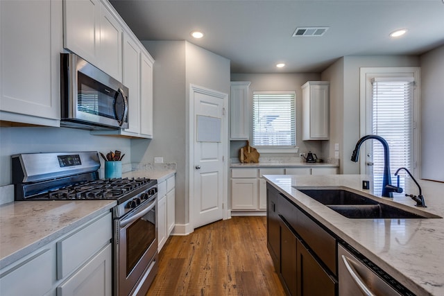 kitchen with a sink, plenty of natural light, stainless steel appliances, and wood finished floors