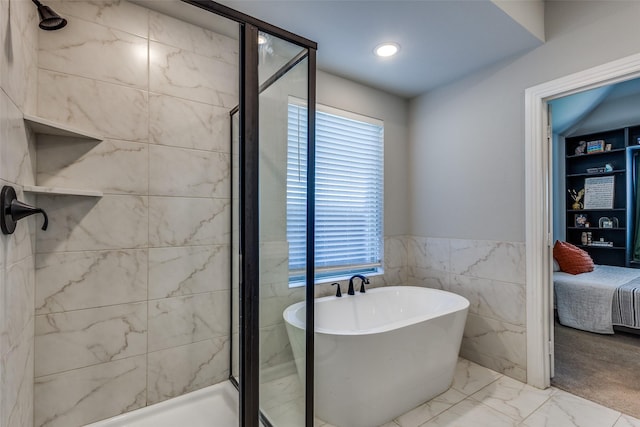 bathroom featuring ensuite bathroom, a soaking tub, tile walls, and a shower stall