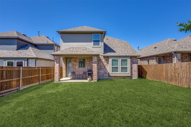 back of house with a fenced backyard, a patio, a yard, and brick siding
