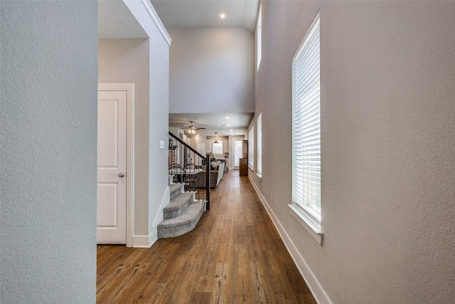 hall with a textured wall, wood finished floors, and stairway