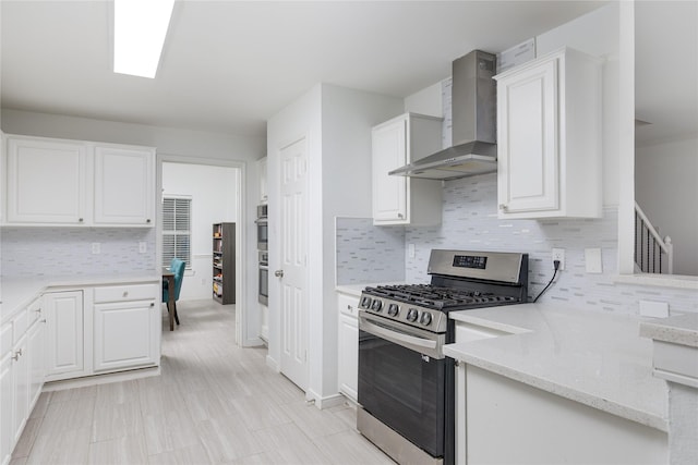 kitchen featuring stainless steel appliances, wall chimney exhaust hood, white cabinets, and tasteful backsplash
