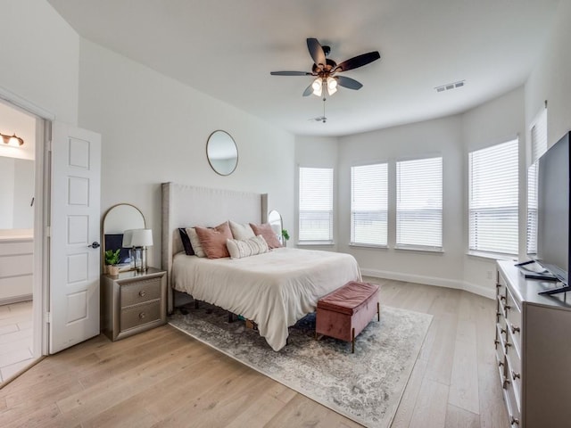 bedroom featuring a ceiling fan, ensuite bath, light wood-style flooring, and visible vents