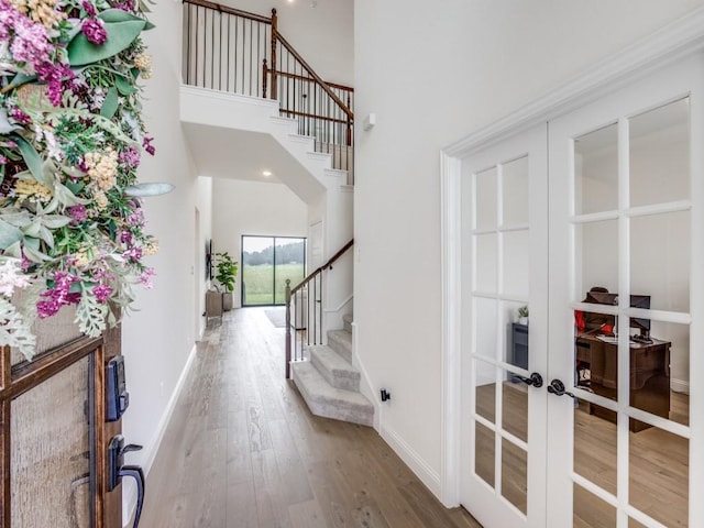 entryway with a high ceiling, french doors, stairs, baseboards, and wood finished floors