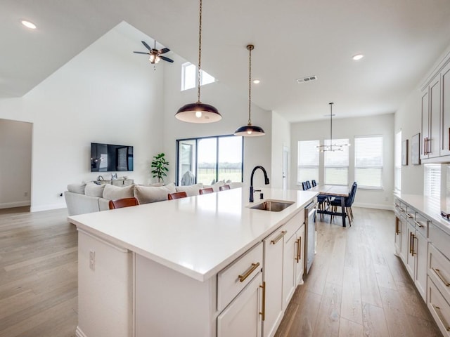 kitchen with light wood-style flooring, a sink, ceiling fan with notable chandelier, and dishwasher