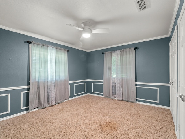 empty room with carpet floors, crown molding, and visible vents