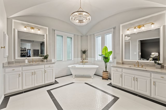 full bath with an inviting chandelier, a sink, and two vanities