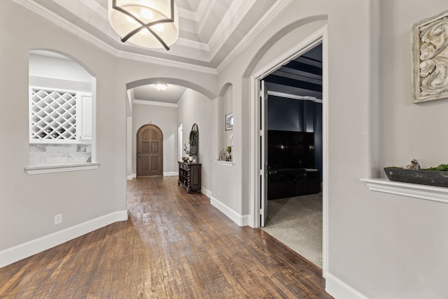 foyer entrance featuring arched walkways, baseboards, ornamental molding, and wood finished floors