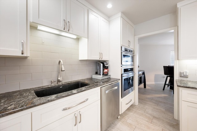 kitchen featuring a sink, appliances with stainless steel finishes, white cabinets, and backsplash