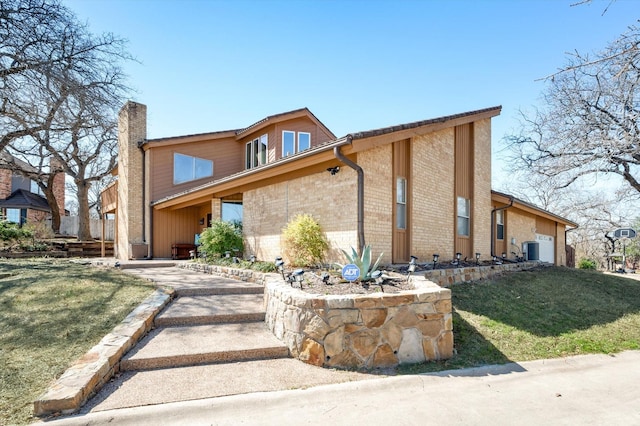 view of front of property featuring central air condition unit, brick siding, a chimney, and a front yard