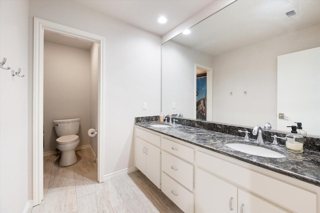 full bathroom with visible vents, a sink, double vanity, and toilet