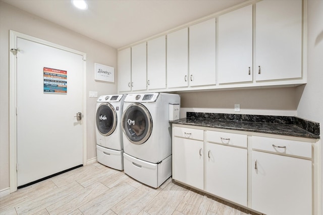 laundry room with light wood-type flooring, cabinet space, baseboards, and washer and dryer
