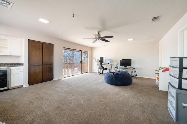 interior space with carpet floors, ceiling fan, beverage cooler, and visible vents