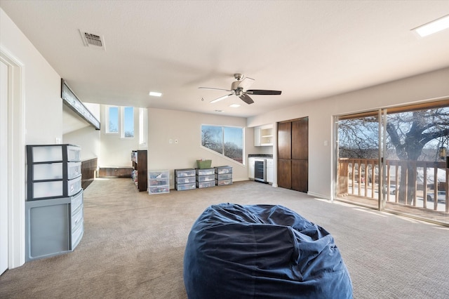 sitting room with ceiling fan, visible vents, a fireplace, wine cooler, and carpet flooring