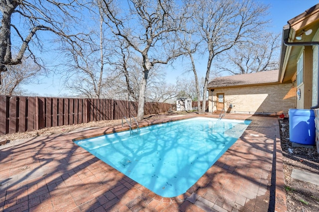 view of pool featuring a storage unit, a fenced backyard, a patio area, and a fenced in pool