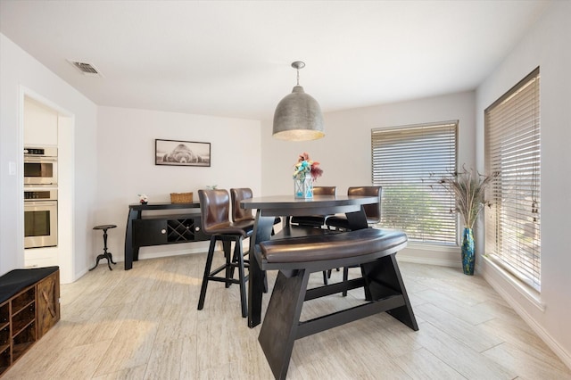 dining room with baseboards, visible vents, and light wood finished floors