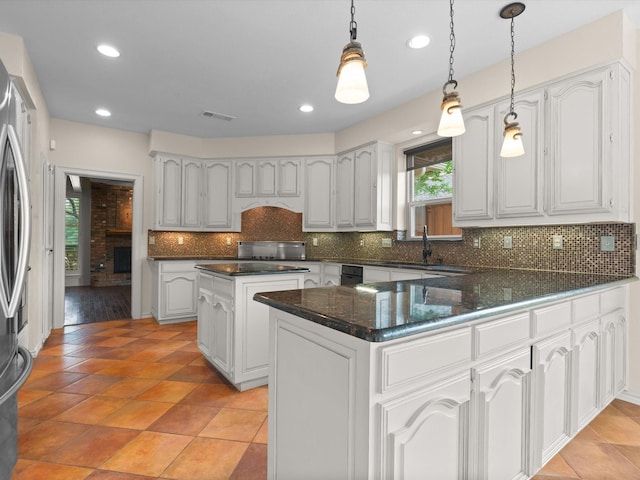 6916 April Way Cir, Plano, TX 75023 - kitchen with a sink, a peninsula, backsplash, white cabinets, and hanging light fixtures