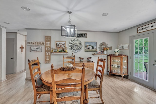 dining area with crown molding, light wood-style floors, and a chandelier
