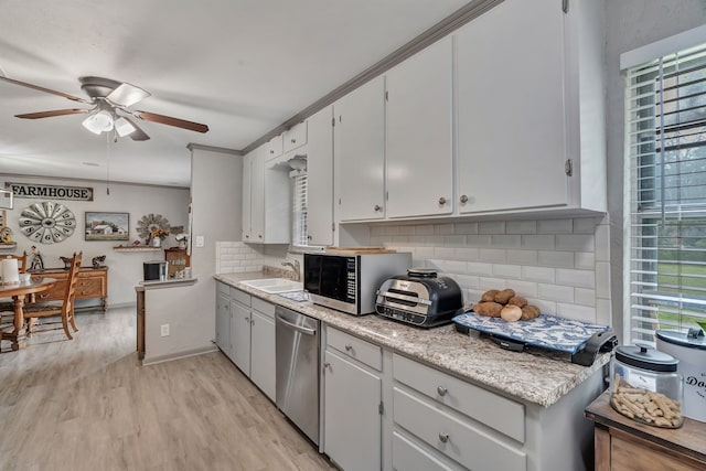kitchen with appliances with stainless steel finishes, plenty of natural light, backsplash, and a ceiling fan