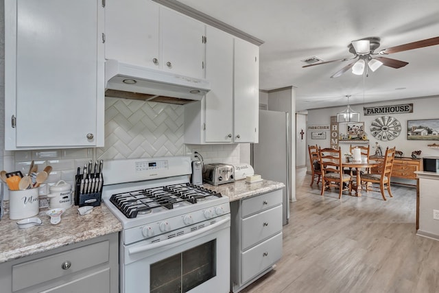 kitchen featuring under cabinet range hood, a ceiling fan, white range with gas cooktop, and tasteful backsplash