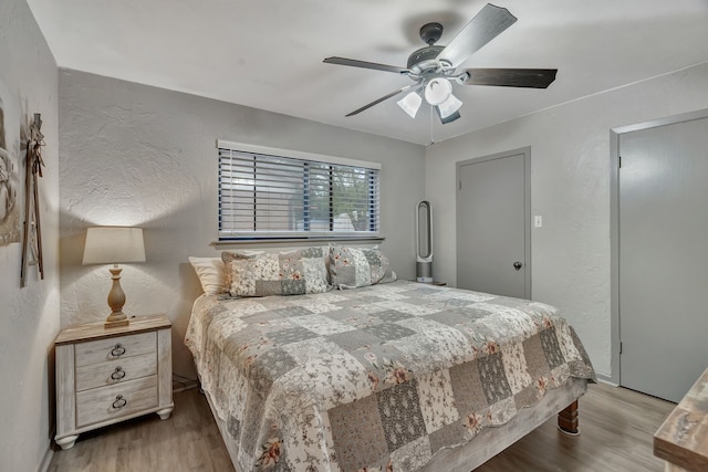 bedroom featuring a textured wall, ceiling fan, and wood finished floors