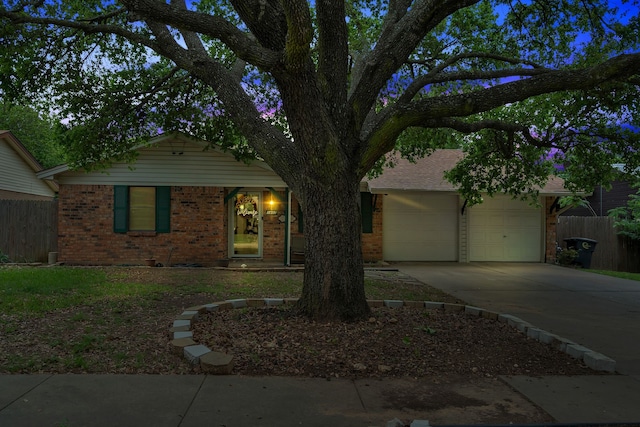 view of front of home featuring concrete driveway, brick siding, and fence