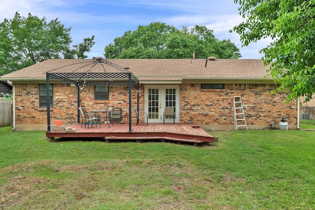 rear view of property featuring a lawn, french doors, a deck, and brick siding