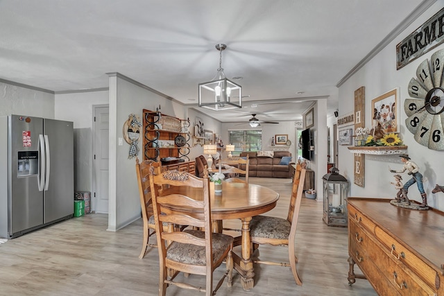 dining area with ornamental molding, ceiling fan with notable chandelier, and light wood-style floors
