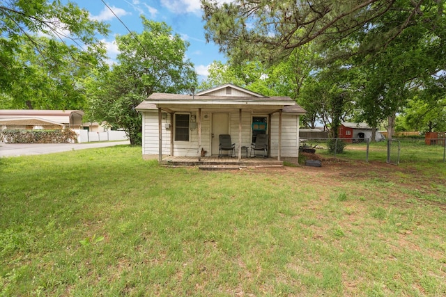 back of property with a lawn, fence, and a porch