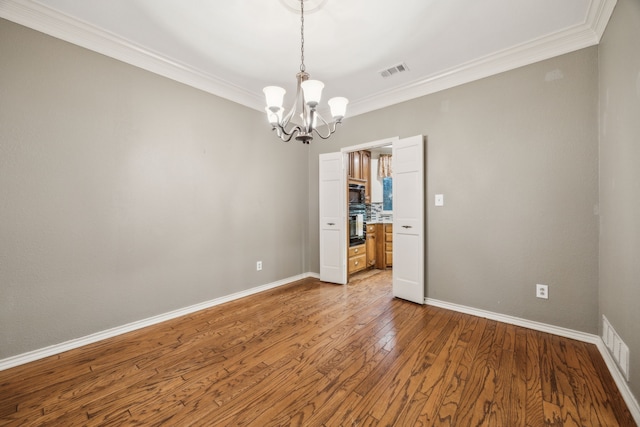 unfurnished room with crown molding, visible vents, an inviting chandelier, and wood finished floors