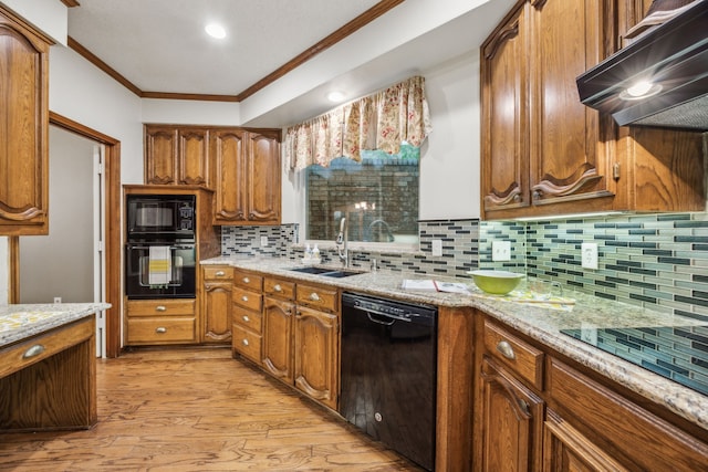 kitchen featuring crown molding, a sink, black appliances, light wood finished floors, and under cabinet range hood