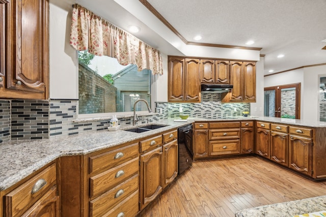 kitchen featuring ornamental molding, under cabinet range hood, brown cabinets, a sink, and black appliances