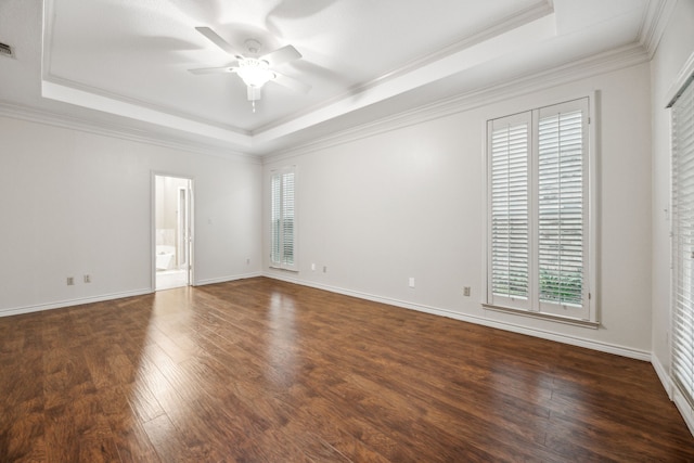 unfurnished room with plenty of natural light, a ceiling fan, a tray ceiling, and dark wood-type flooring