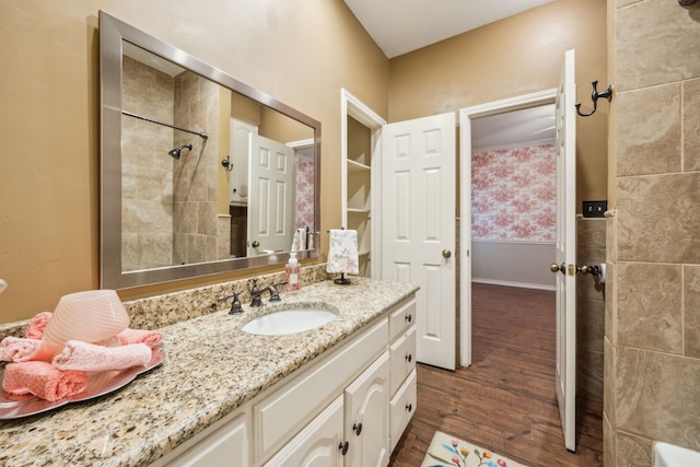 bathroom featuring a tile shower, wood finished floors, and vanity