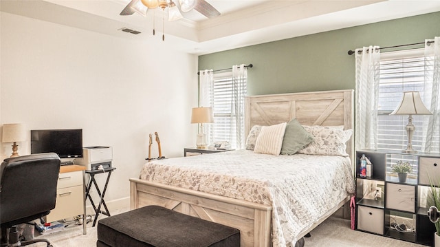 carpeted bedroom featuring a ceiling fan, visible vents, crown molding, a raised ceiling, and baseboards