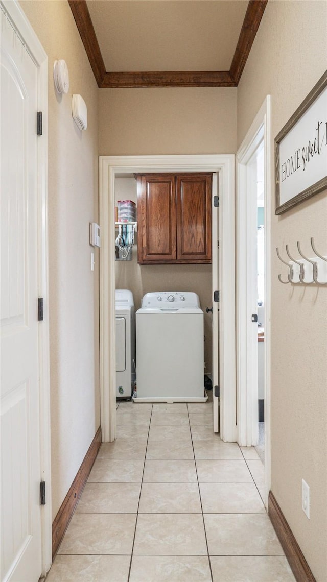 laundry area with washing machine and clothes dryer, cabinet space, baseboards, ornamental molding, and light tile patterned flooring