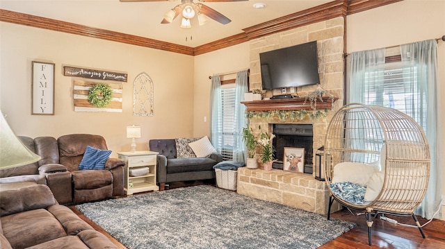 living area with crown molding, ceiling fan, a large fireplace, and wood finished floors