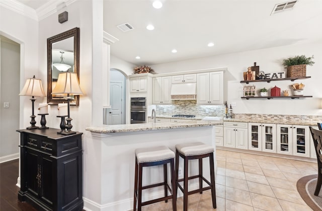kitchen featuring visible vents, ventilation hood, appliances with stainless steel finishes, and white cabinetry