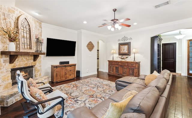 living area with a ceiling fan, visible vents, arched walkways, a fireplace, and wood finished floors