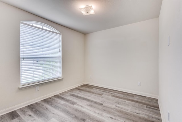 spare room with baseboards, plenty of natural light, and wood finished floors