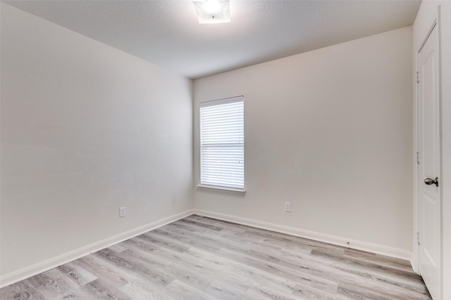 spare room with baseboards and light wood-type flooring